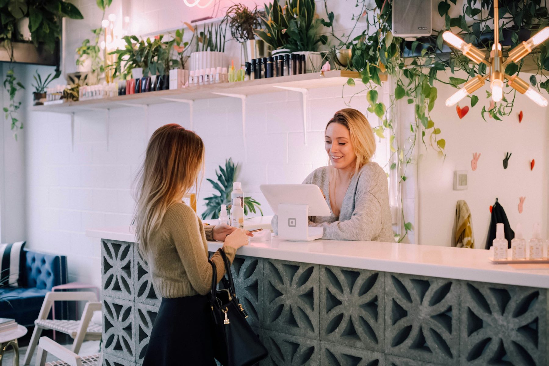 Une cliente est accueillie au comptoir d’une boutique remplie de plantes