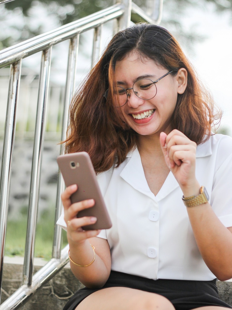 Une jeune femme sourit en réservant sur son téléphone