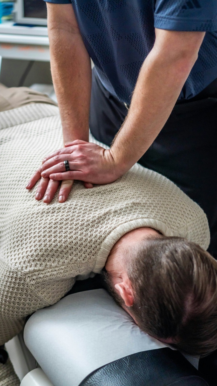 Un chiropraticien ajuste le haut du dos d’un patient