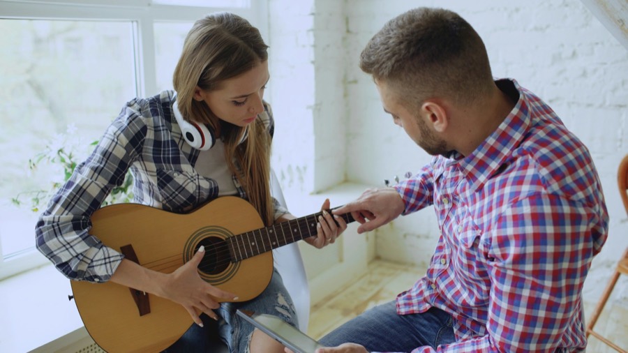 Un professeur montre un accord de guitare à une élève