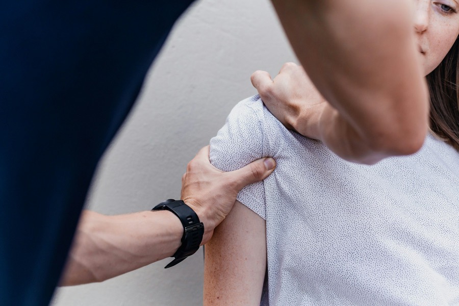 Une physiothérapeute examine l’épaule d’un patient